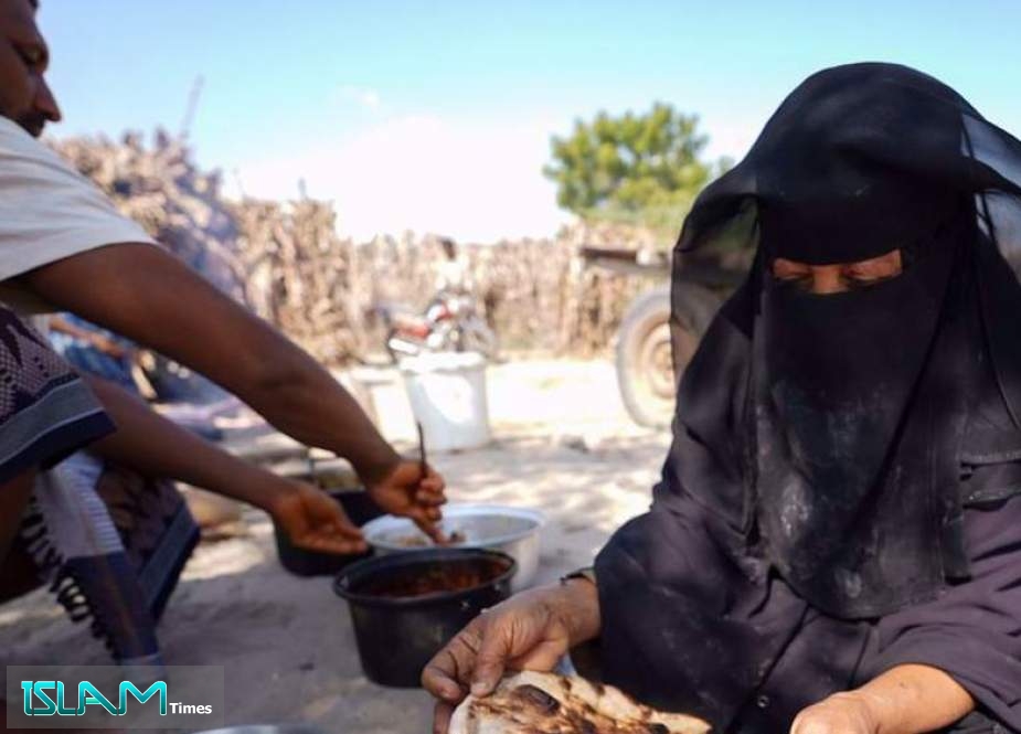 The file photo shows a woman baking bread at her shelter in Khanfar District, Yemen.
