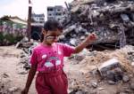 A Palestinian girl with a national flag painted on her face plays amidst the rubble of buildings destroyed by Israel