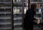 A woman takes a jug of milk off an empty shelf at a Giant Food Supermarket, January 12, 2022 in Springfield, Virginia, USA.