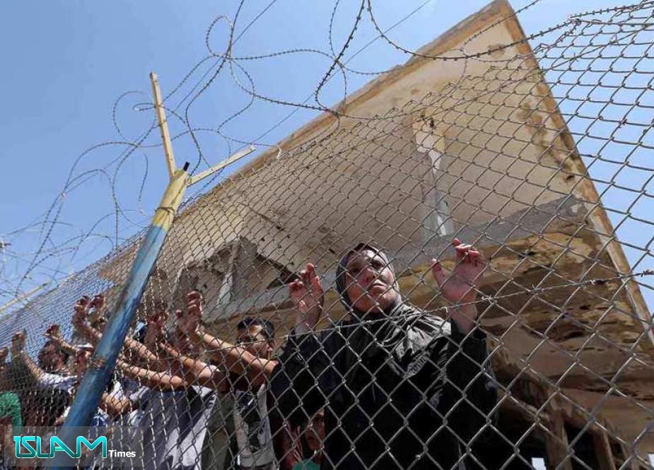 File photo shows Palestinians gathering in front of the gate of Rafah border crossing between Egypt and the Gaza Strip during a protest against the Israeli regime’s blockade of the coastal territory.