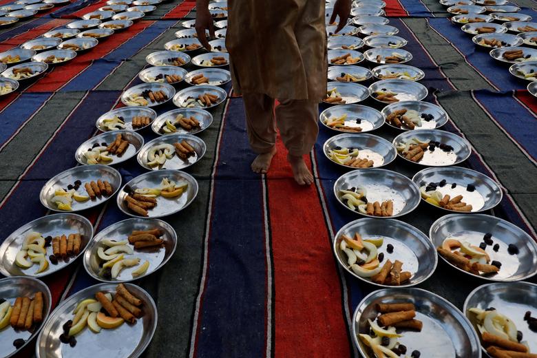 A man walks to inspect food panes before iftar, or breaking fast, during the fasting month of Ramadan, in Karachi, Pakistan, March 23, 2023.