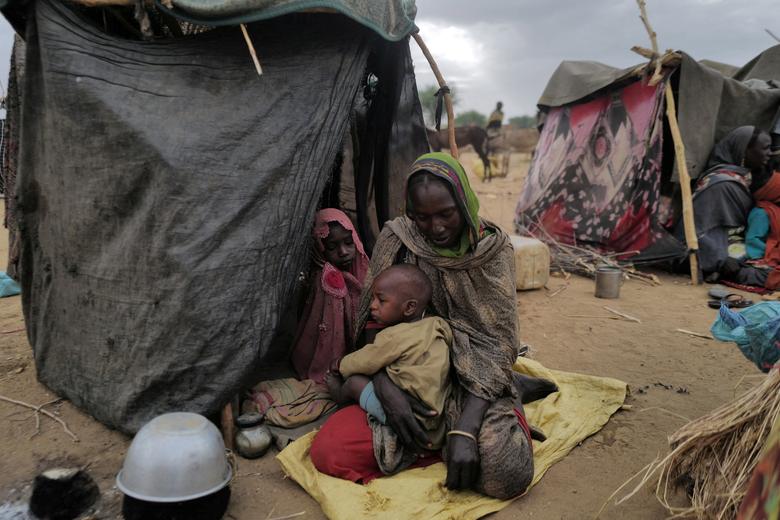 Mekka, 30, a Sudanese refugee who has fled the violence in Sudan's Darfur region, sits with her children beside their makeshift shelter near the border between Sudan and Chad in Koufroun, Chad, May 11, 2023.