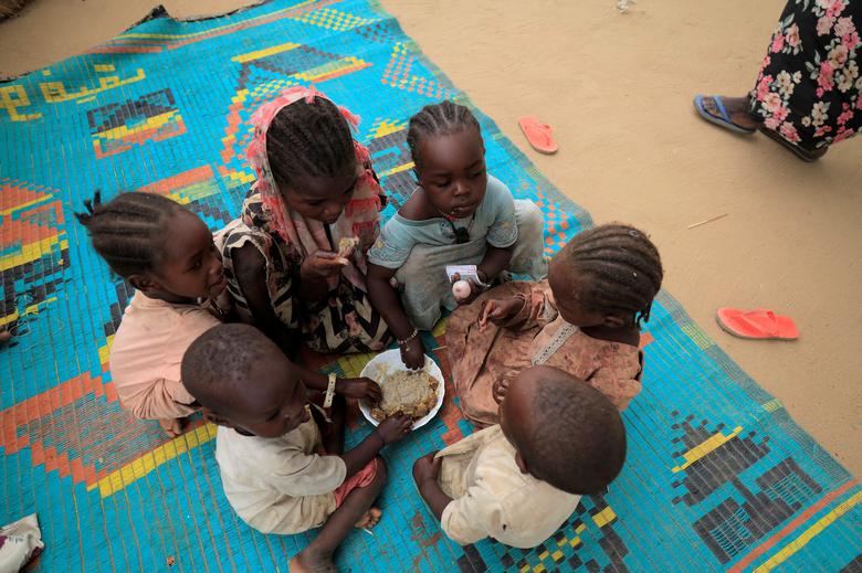 Sudanese refugee children who have fled the violence in Sudan's Darfur region, eat their breakfast beside makeshift shelters near the border between Sudan and Chad in Koufroun, Chad, May 11.