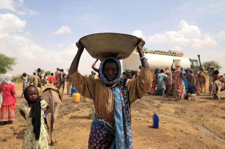 A Sudanese refugee woman, who fled the violence in Sudan's Darfur region, carries a basin of water as she walks toward her makeshift shelter near the border between Sudan and Chad in Koufroun, Chad, May 10.