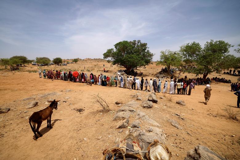 Sudanese refugees, who have fled the violence in their country, walk in line to receive food rations from World Food Programme (WFP), near the border between Sudan and Chad in Koufroun, Chad, May 9.
