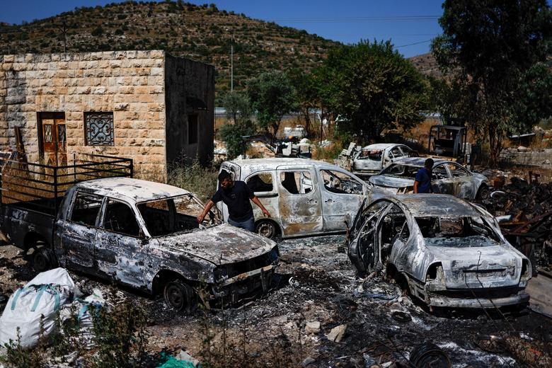 Palestinians check burned vehicles after an attack by Israeli settlers near Ramallah in the Israeli-occupied West Bank, June 21,2023.