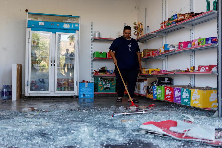 A Palestinian man clears broken glass in a store damaged in an attack by Israeli settlers near Ramallah in the Israeli-occupied West Bank, June 21,2023.