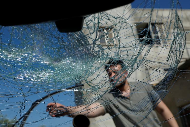 A Palestinian man checks a damaged vehicle after an attack by Israeli settlers near Ramallah in the Israeli-occupied West Bank, June 21, 2023.
