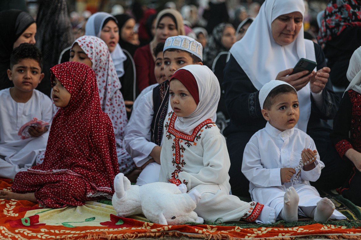 Children join their parents at Eid al-Adha prayers at an open area in Gaza City.