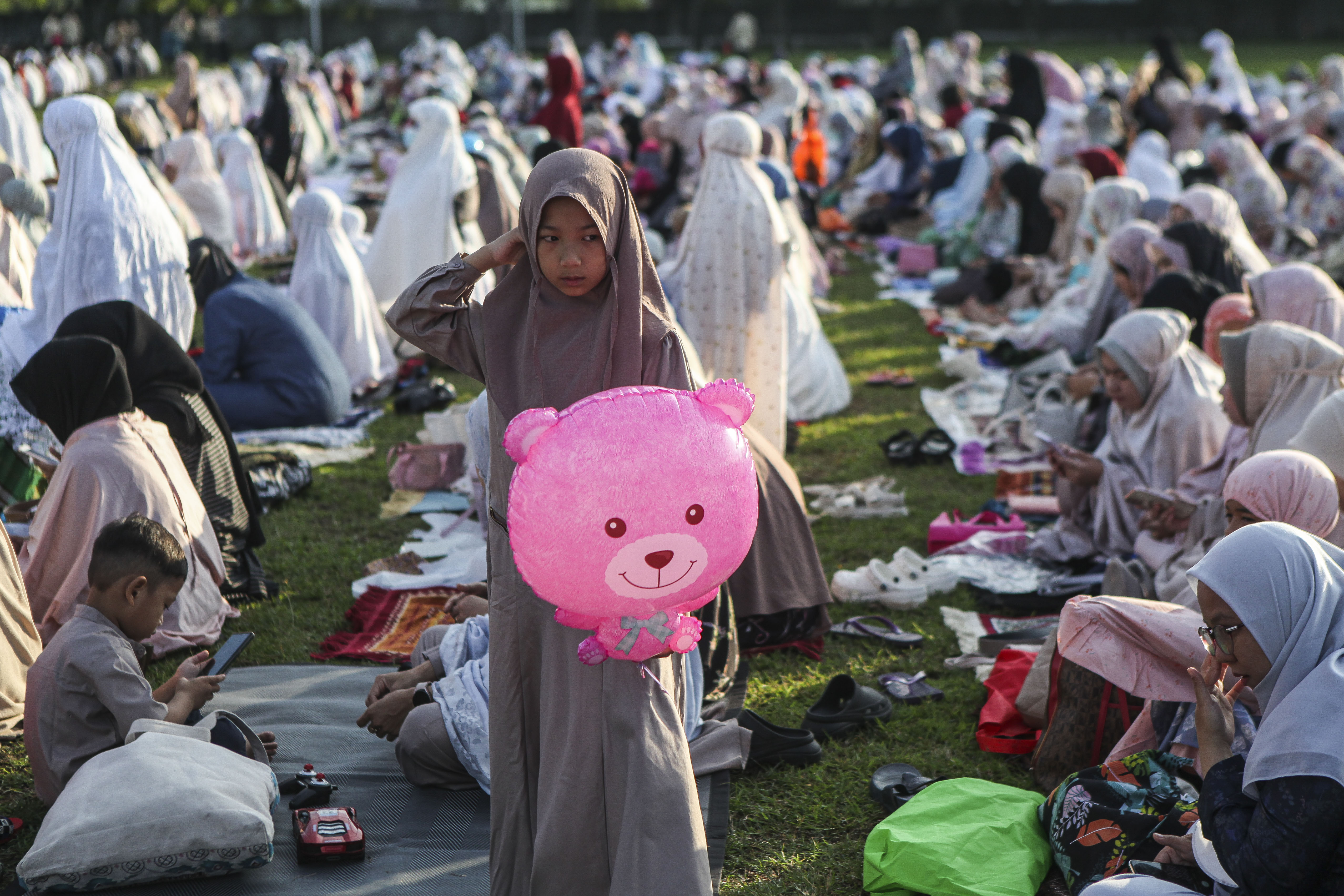 A girl holds a balloon as Indonesian Muslims attend Eid al-Adha prayers on a football field in Depok, West Java, Indonesia.