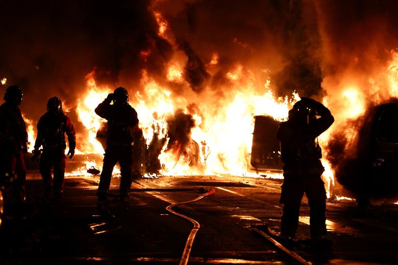Firefighters stand as they extinguish burning vehicles during clashes between protesters and police, in the Paris suburb of Nanterre, France, June 28.