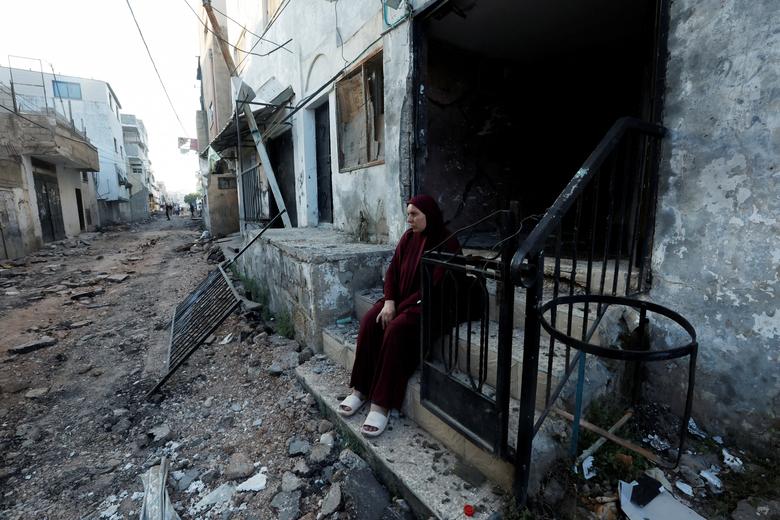 A Palestinian woman sits in front of a damaged building after the Israeli army's withdrawal from the Jenin camp, in Jenin, in the Israeli-occupied West Bank July 5, 2023.
