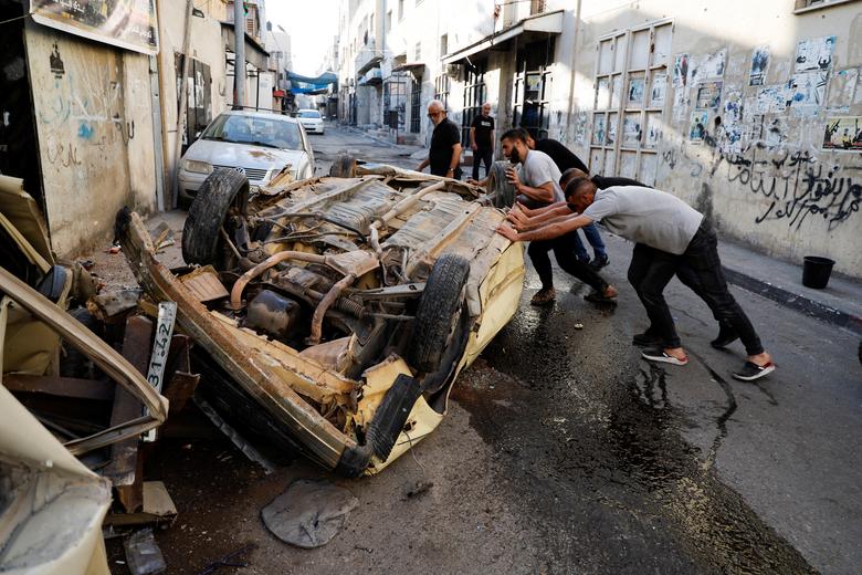 Palestinians try to move a damaged car after the Israeli army's withdrawal from the Jenin camp, in Jenin, in the Israeli-occupied West Bank July 5.