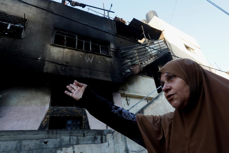 Seorang wanita Palestina memberi isyarat di dekat bangunan yang rusak setelah penarikan tentara Israel dari kamp Jenin, di Jenin, di Tepi Barat yang diduduki Israel 5 Juli