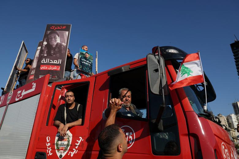 People standing on a fire engine hold images of the victims of the August 2020 Beirut port blast during a march in Beirut, August 4.