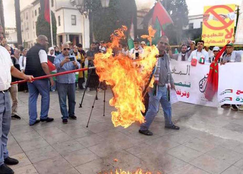Protester burns an Israeli flag in front of the parliament building in the capital Rabat.jpeg