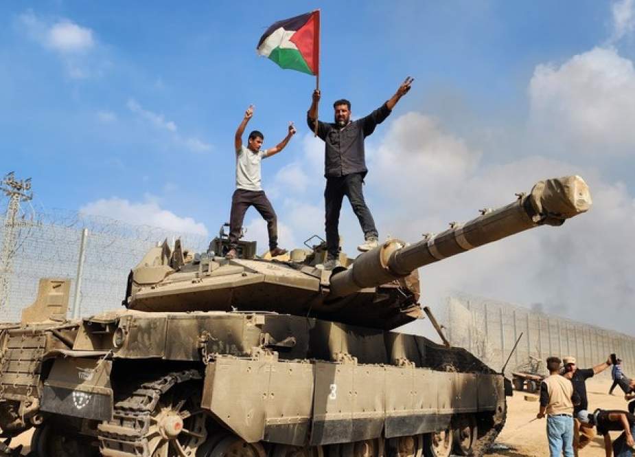 Palestinians stand atop of a destroyed Israeli tank.jpg