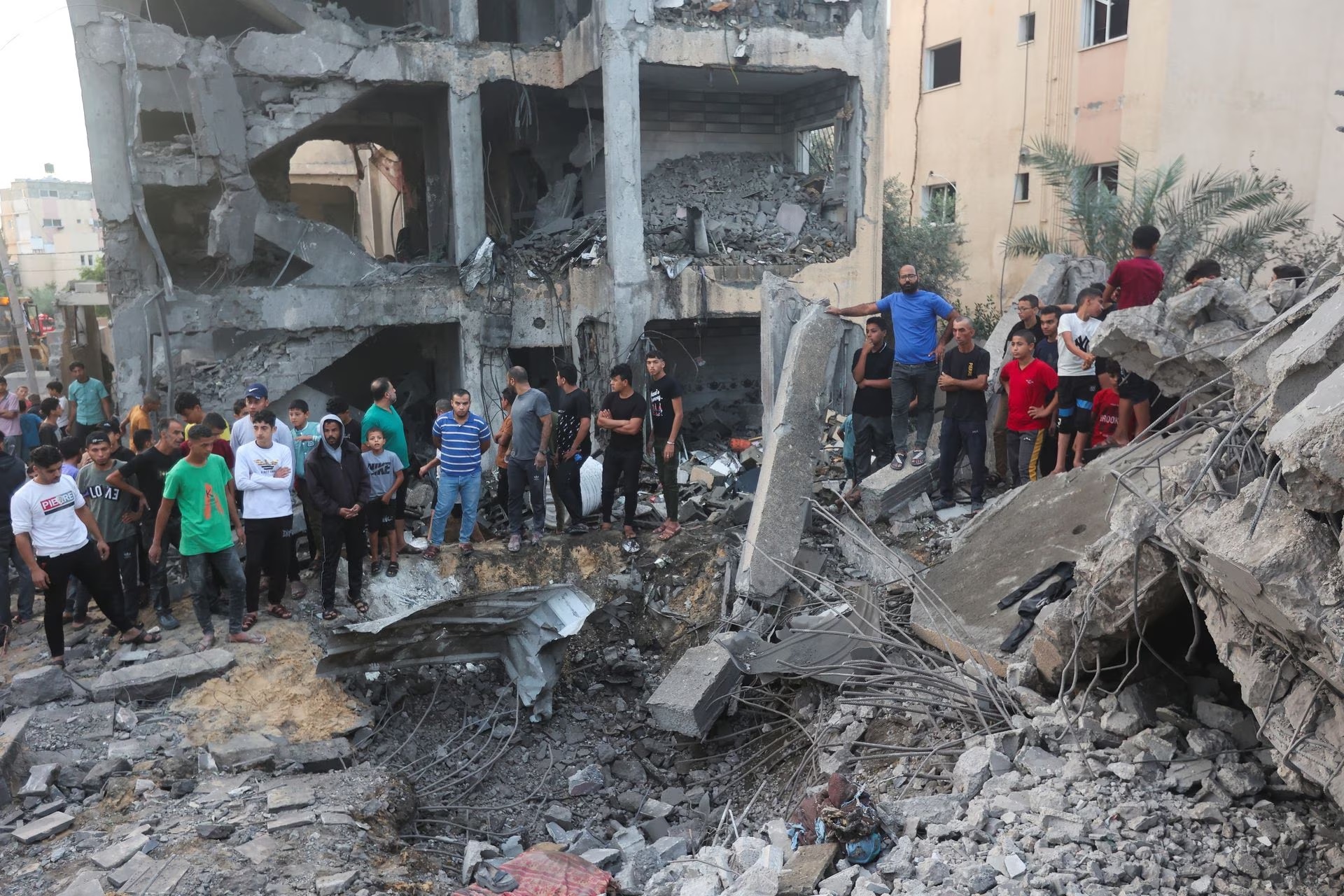 People gather as Palestinians work to remove casualties from under the rubble of a house destroyed by Israeli strikes, in Khan Younis in the southern Gaza Strip October 17, 2023.