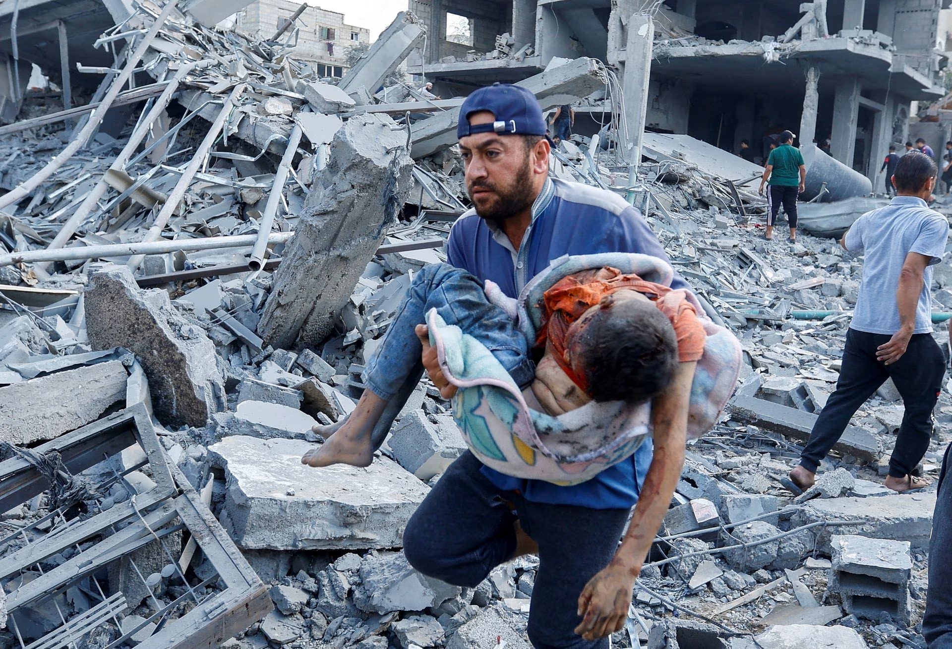 A Palestinian man carries a child casualty following Israeli strikes on houses in Rafah in the southern Gaza Strip, October 17.