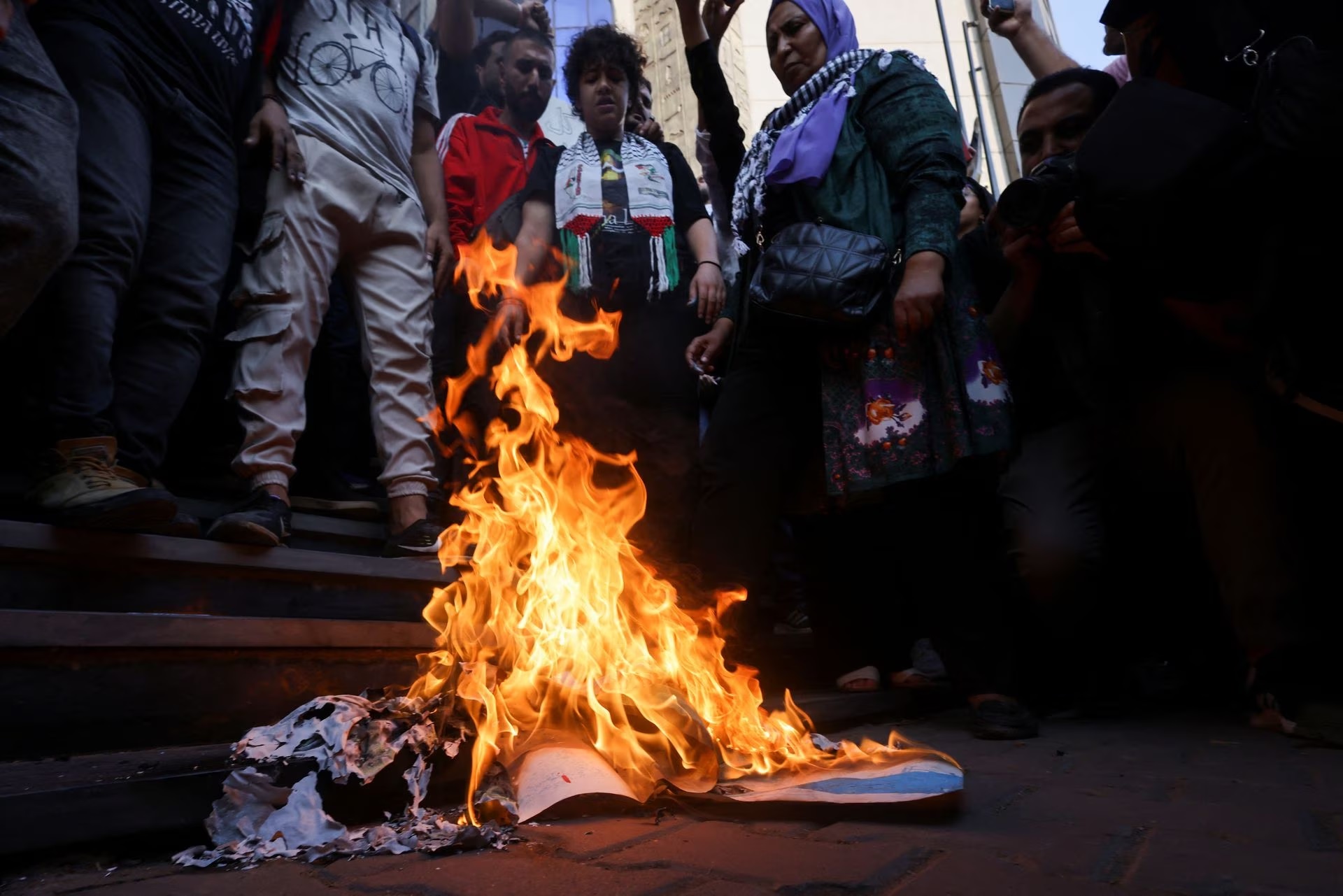 Egyptian dmonstrators stand near burning banners depicting the Israeli flag as they protest against Israel and the USA in support of Palestinians for those killed in an Israeli blast at Al-Ahli hospital in Gaza.