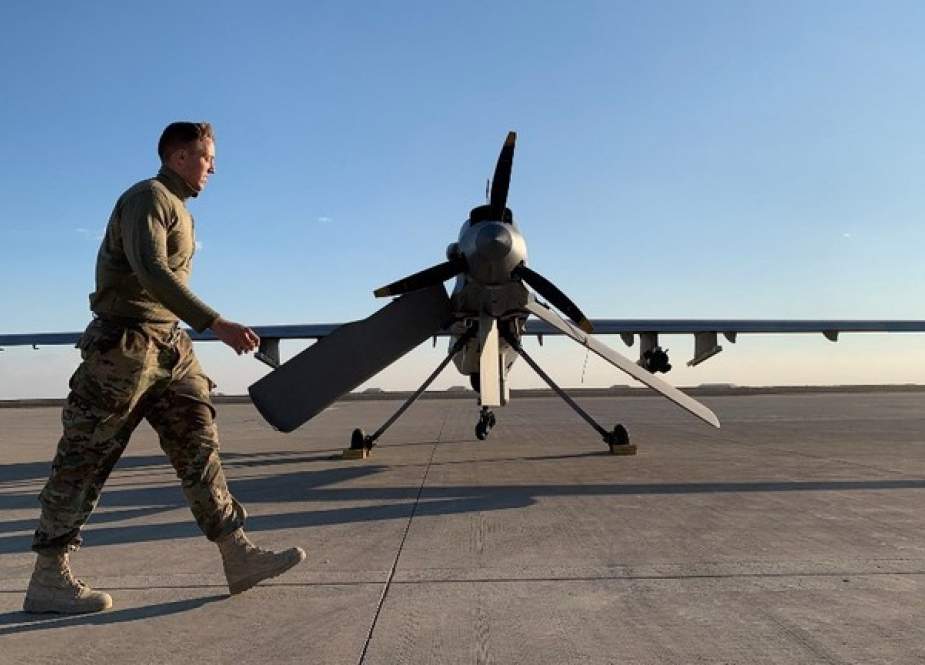 American service member walks past a drone in the al-Asad airbase in Anbar, Iraq