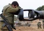 Israeli soldier rests his head on the gun barrel of a self-propelled artillery howitzer