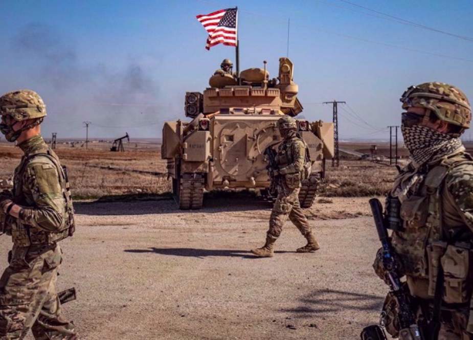 US soldiers walk while on patrol by the Suwaydiyah oil fields in Syria