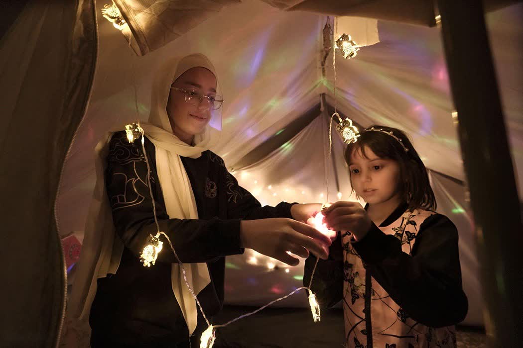 ماہ رمضان کے استقبال کی خاطر فلسطینی بچے اپنے خیموں میں لائٹس روشن کرتے ہوئے