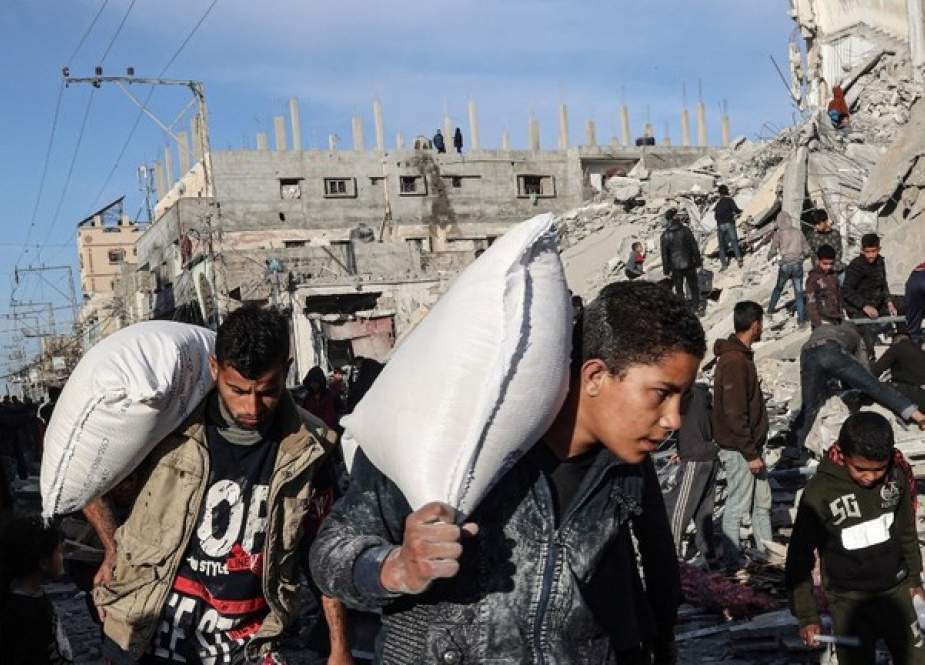 Palestinians walk past buildings destroyed by Israeli airstrikes in Rafah, Gaza
