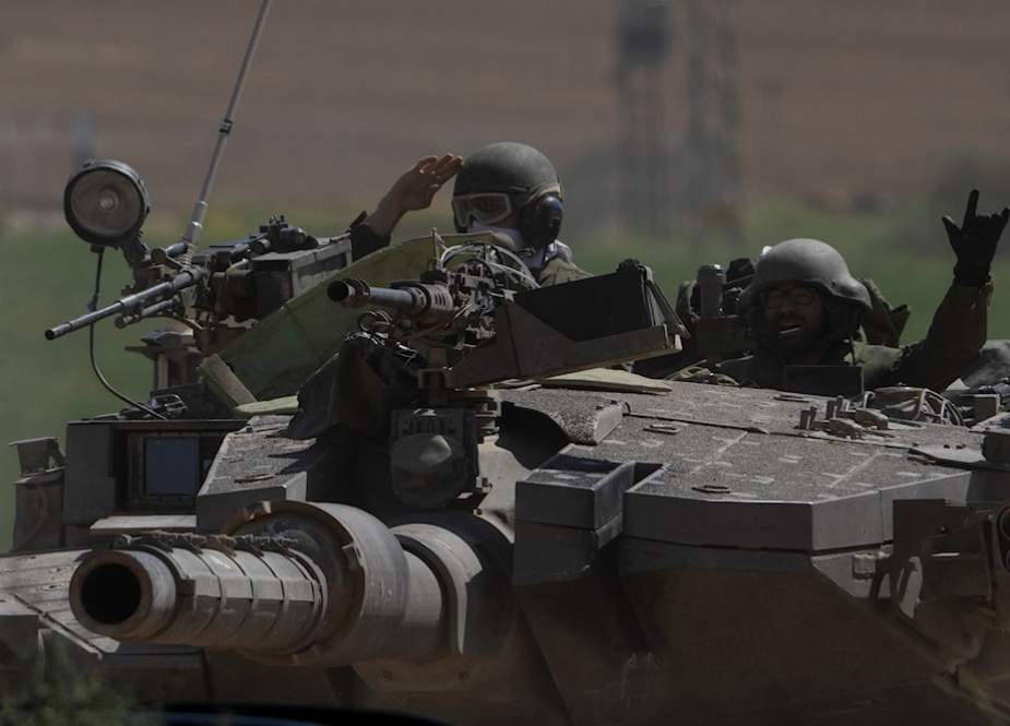 Israeli soldiers move on the top of a tank near the Gaza Strip