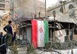 Iranian flag hangs as smoke rises after an Israeli strike on the consular section of the Iranian Embassy in Damascus, Syria