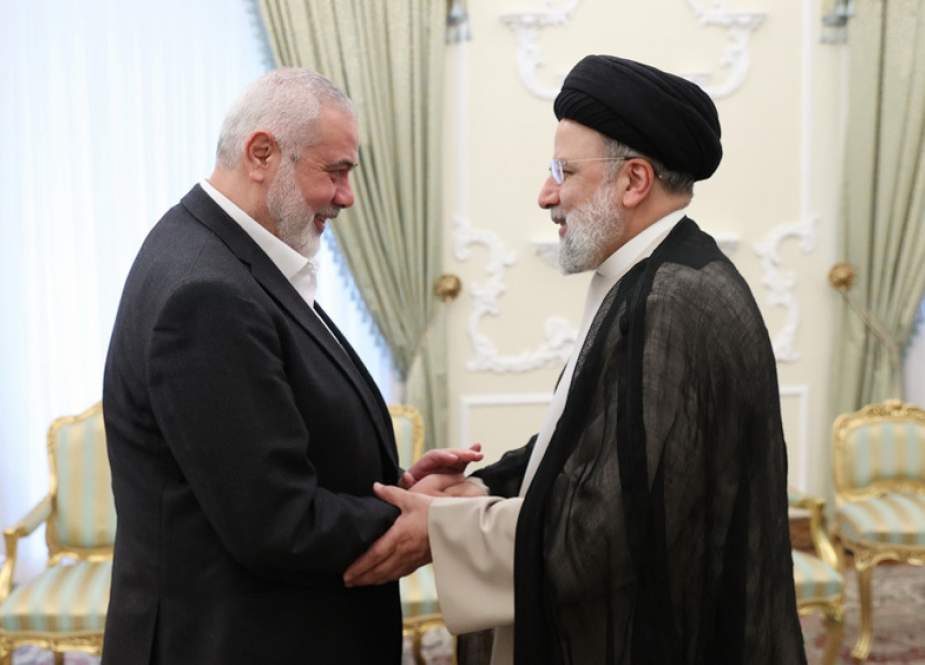 Iranian President Ebrahim Raesi shakes hands with Hamas politburo chief Ismail Haniyeh