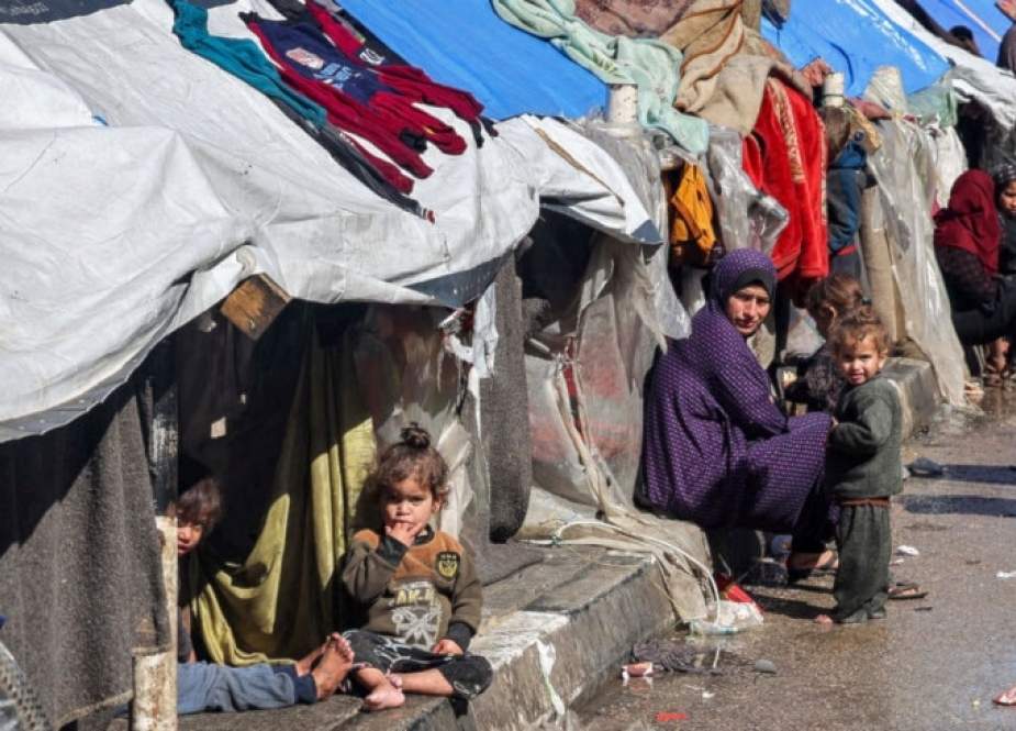 A Palestinian women and children sit outside tents in Rafah, South Gaza