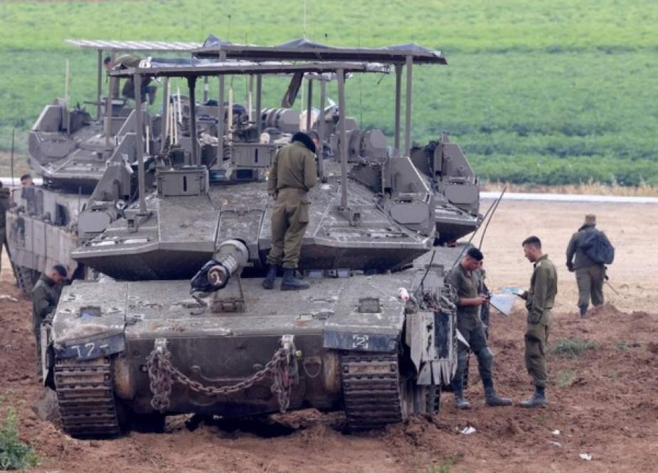 Israeli army troops stand around their tank in an area along the border with the Gaza Strip