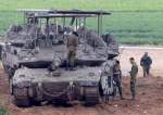 Israeli army troops stand around their tank in an area along the border with the Gaza Strip