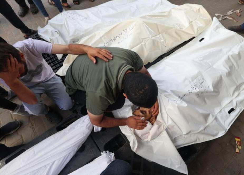 Palestinians mourn by the bodies of relatives killed in Israeli bombardment of Gaza