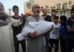 A Palestinian carries a child killed in an Israeli strike in Deir el-Balah, the Gaza Strip