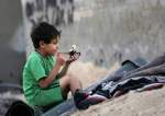 A Palestinian child plays next to empty ammunition containers used by the Israeli occupation in Khan Younis Gaza