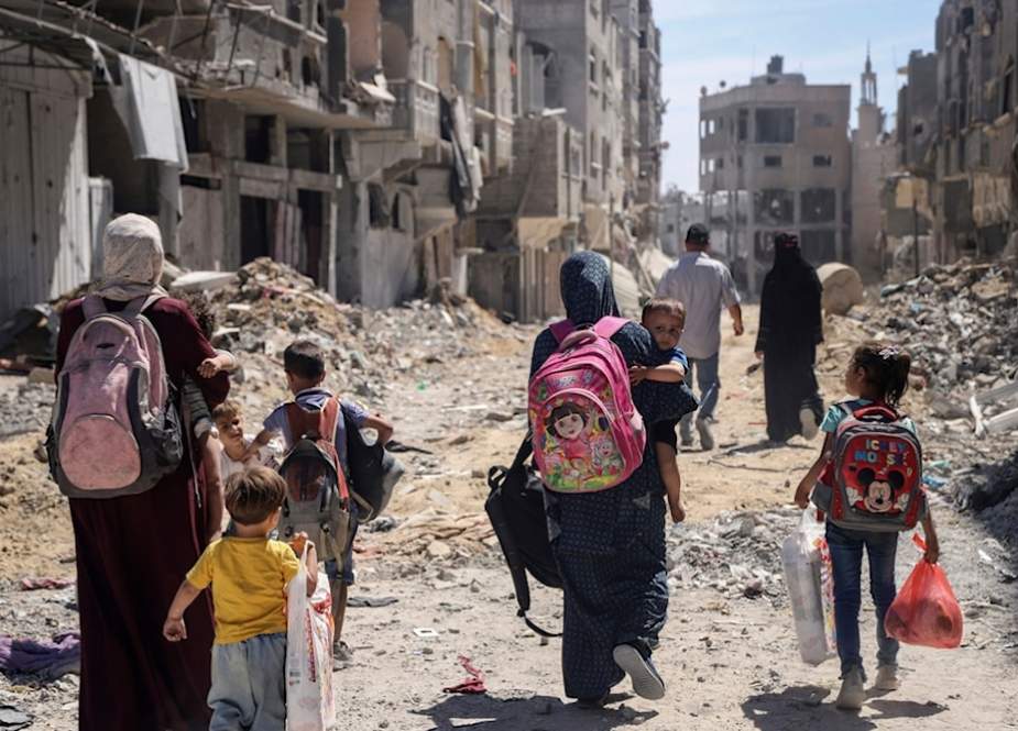 Palestinian women and their children walk through destruction in the wake of an Israeli air and ground attack in Jebaliya, northern Gaza Strip